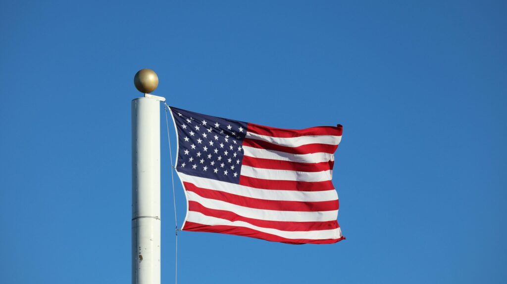 A vibrant American flag waves proudly against a clear blue sky in Elk Grove, California.