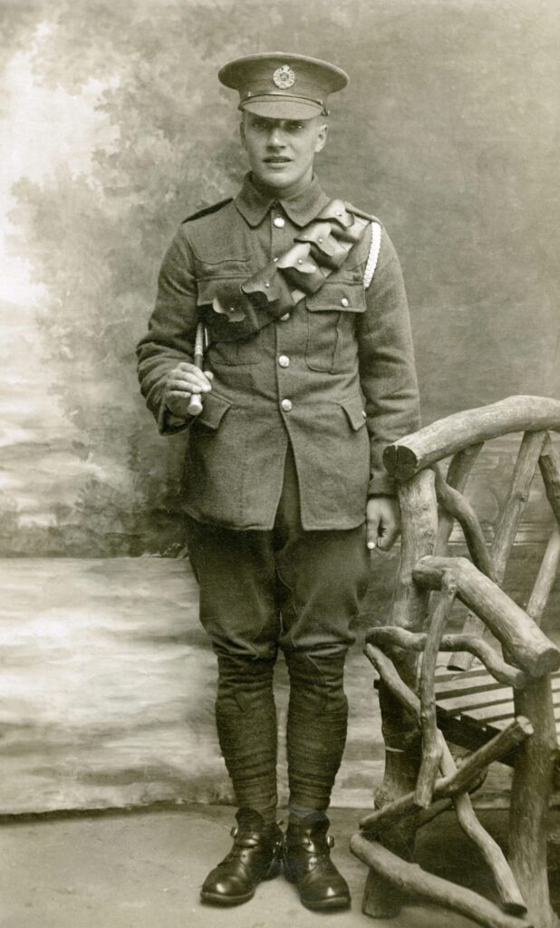 Sepia-toned vintage photo of a soldier in a classic military uniform with a rustic chair.